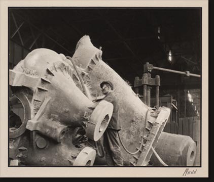 Workmen with pneumatic chipping hammers clean a steel casting. The casting is a turbine casing and weighs 51,000 pounds.