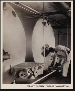 Two of the large, glass-lined, brine-cooled tanks in a Kraft plant. The tested milk, received early in the morning from neighboring farms, is held in these huge tanks during the few hours which must elapse before it is made into cheese. The tanks are thoroughly cleaned and sterilized every day, at the conclusion of cheese making operations.