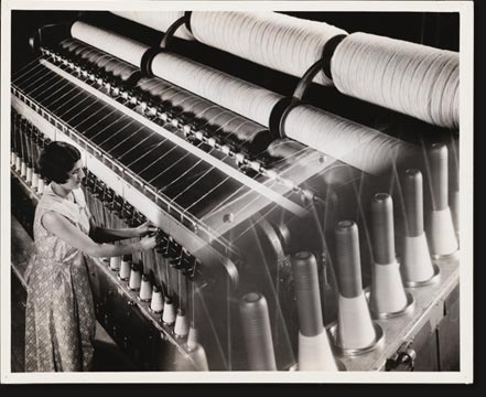 A newer machine for spinning is the frame shown here. The principle is the same as in mule spinning, but the draw is continuous. Running between the two sets of rollers, one of which turns faster than the other, the roving is drawn down to size, while the spindle revolves, twisting the yarn and winding it in the same operation.