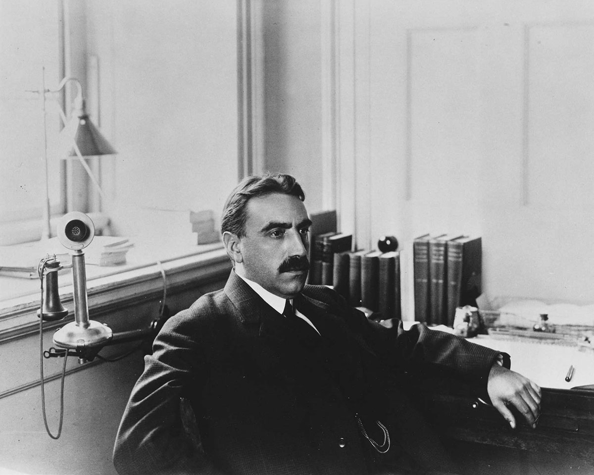 Black and white portrait of HBS Dean Edwin F. Gay seated at a desk in his office.