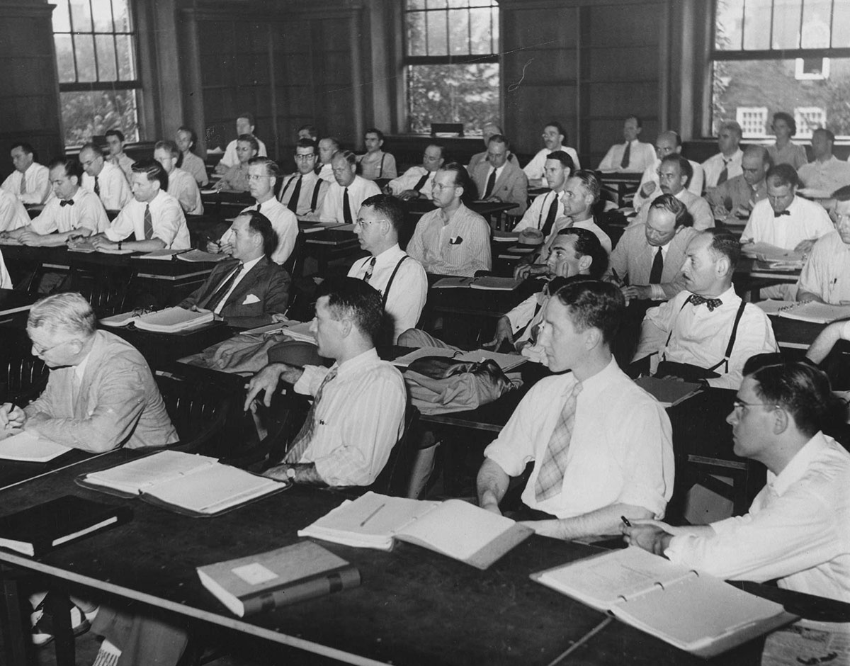 Black and white photograph of male students in the Advanced Management Program, designed for mid-career executives, seated in a classroom.