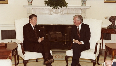 Ronald Reagan and John C. Whitehead seated in the Oval Office.