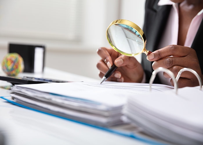 Image of magnifying glass checking figures. (Shutterstock)